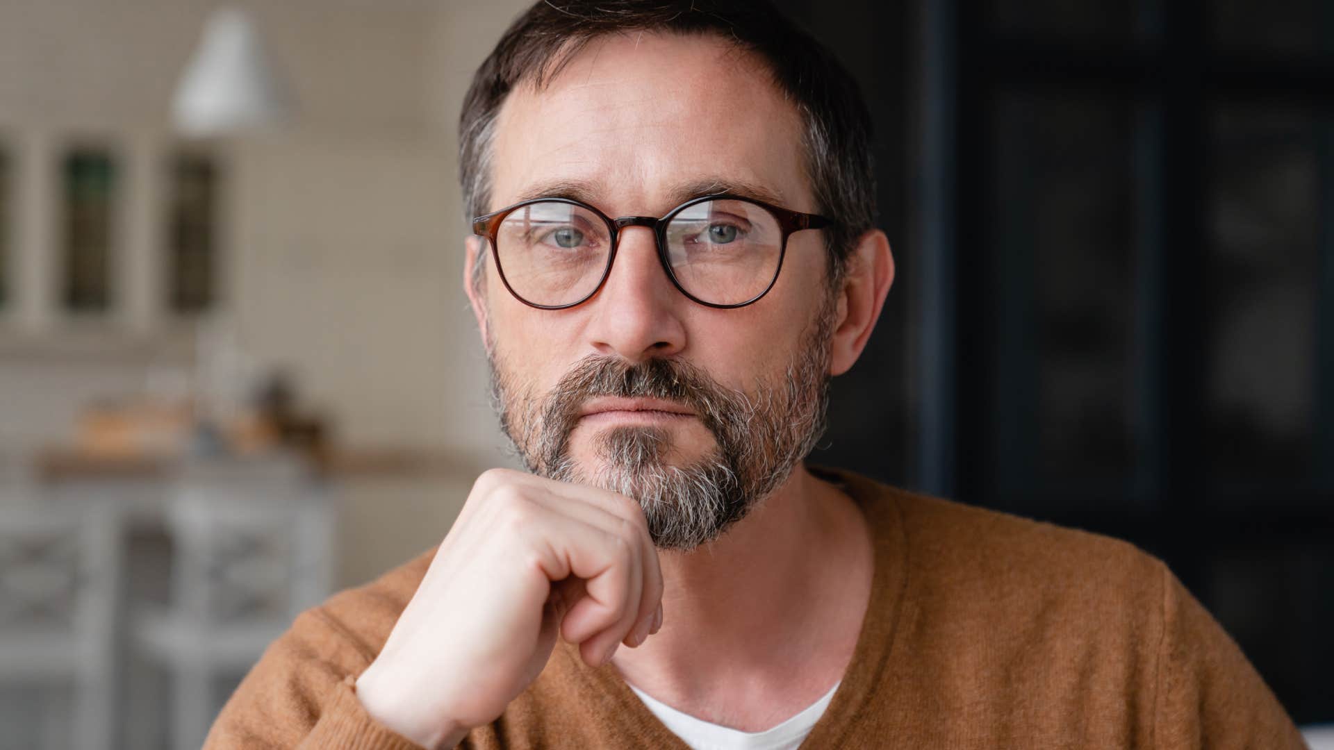 serious man sitting at table with fist on chin