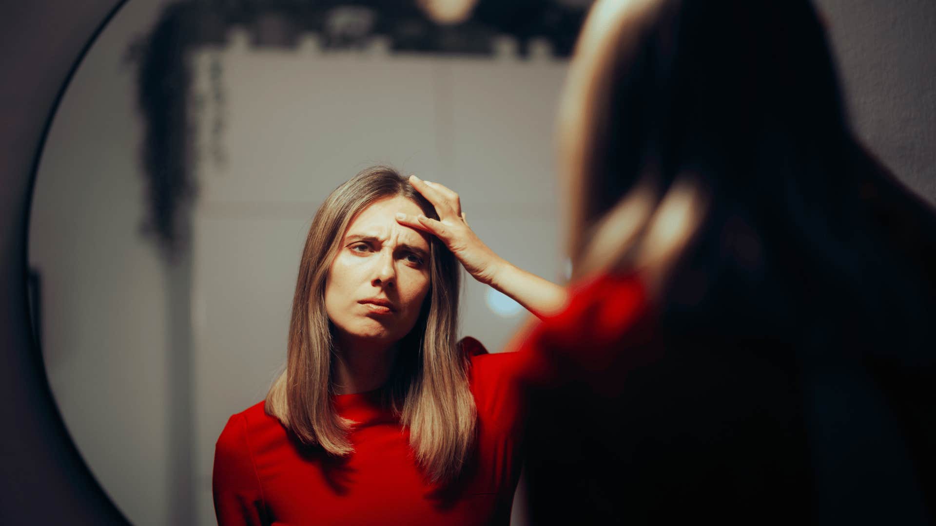 upset woman looking in mirror