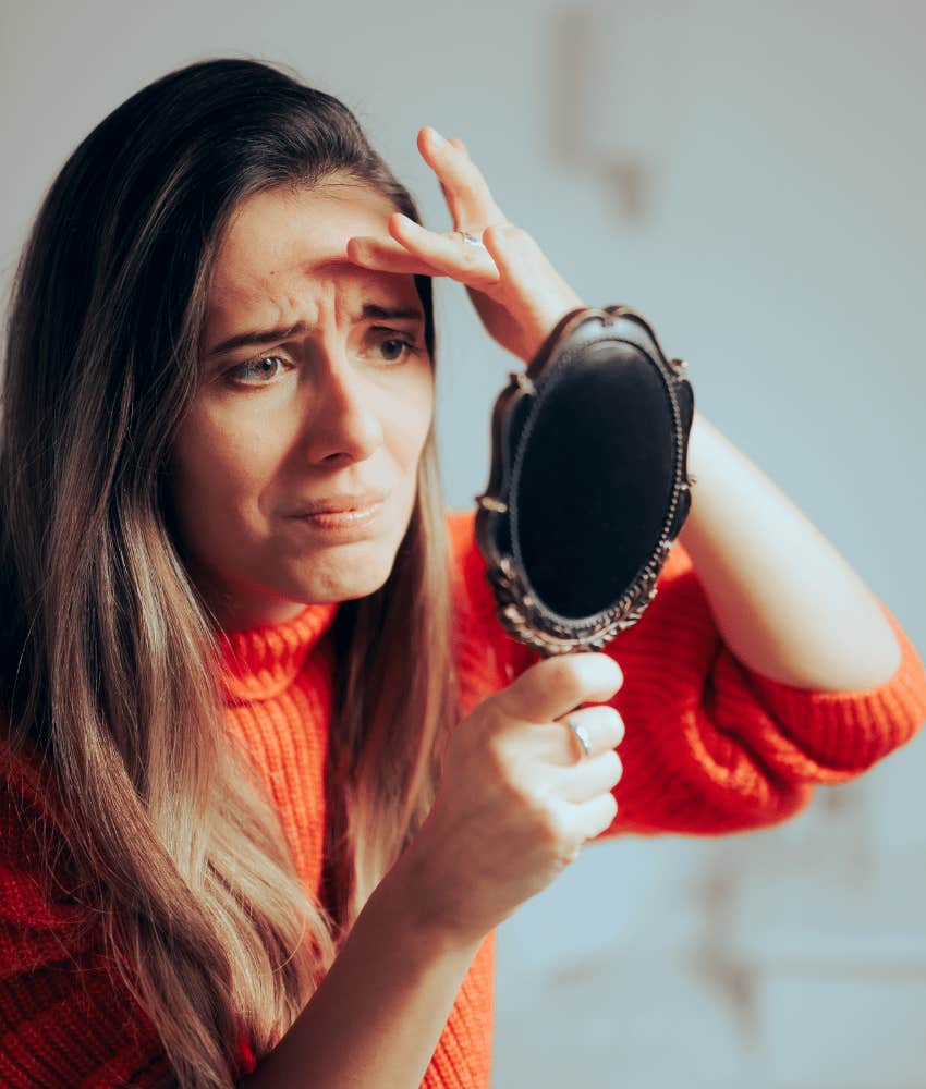 Tired woman checks her skin in mirror