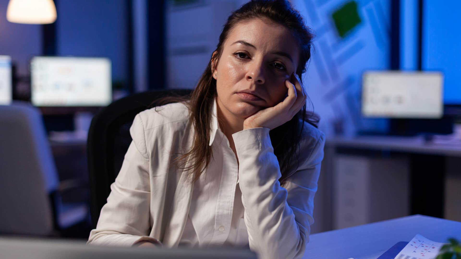 Tired woman sitting in her dark office