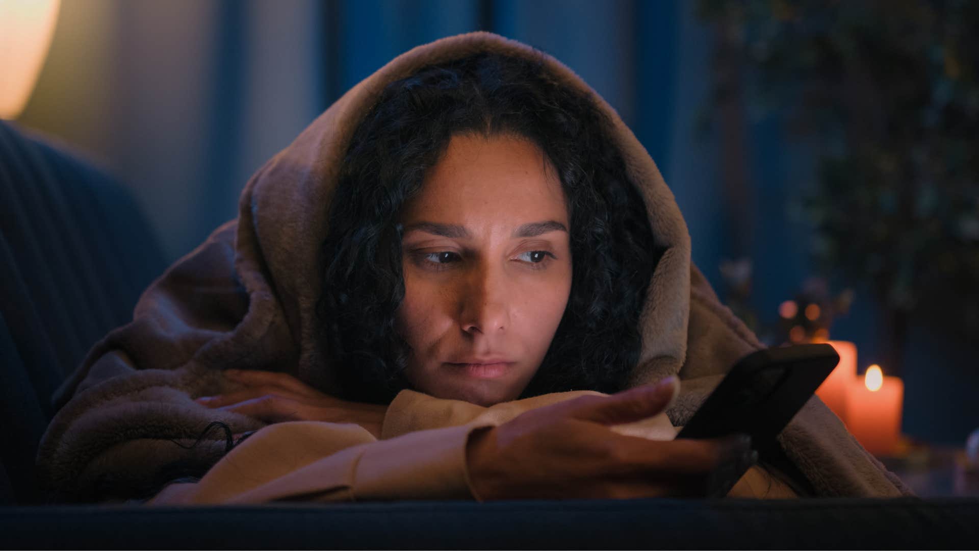 Sad woman looking at her phone in a dark room