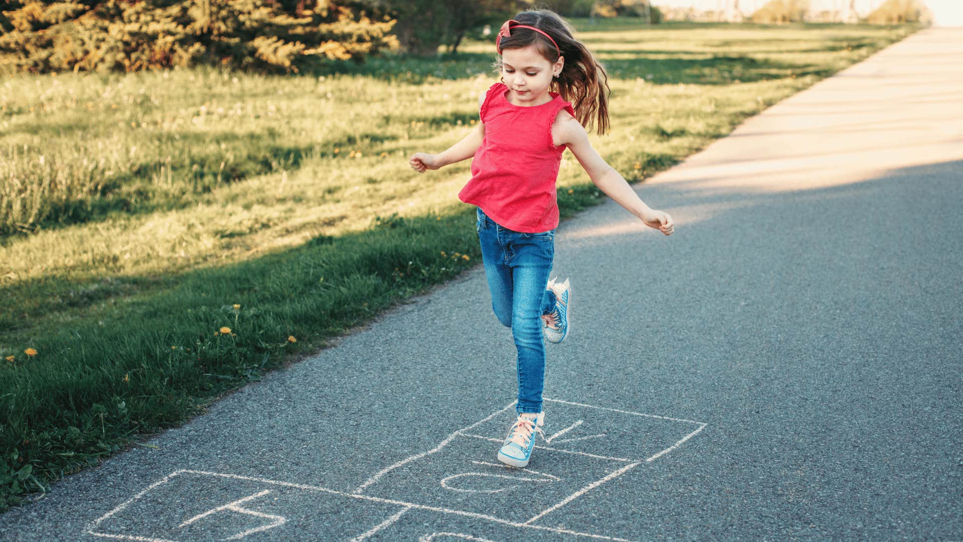 child jumping on one foot playing hopscotch