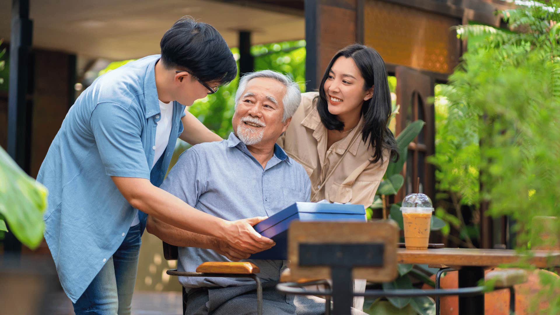 Man and woman give gift to elder man as tradition