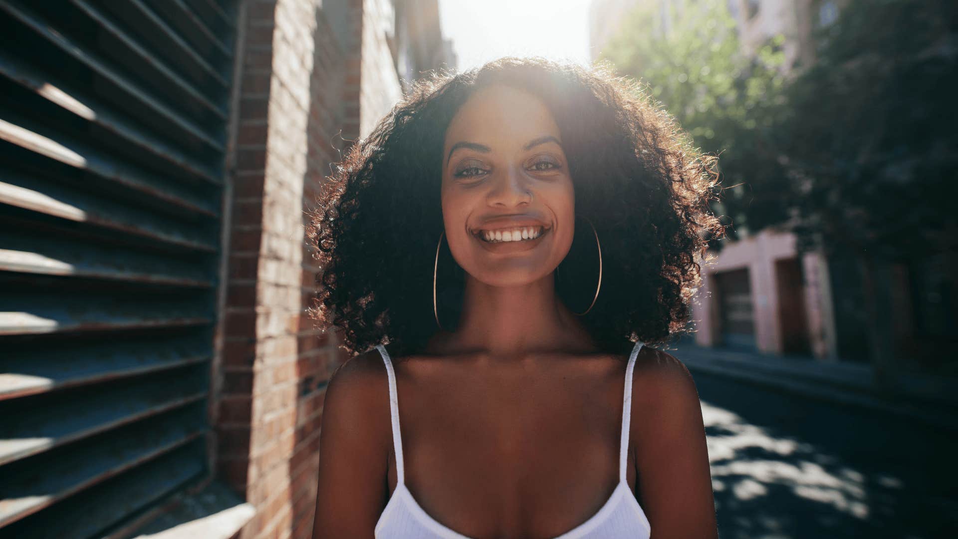 Portrait of smiling young woman with curly hair on road.