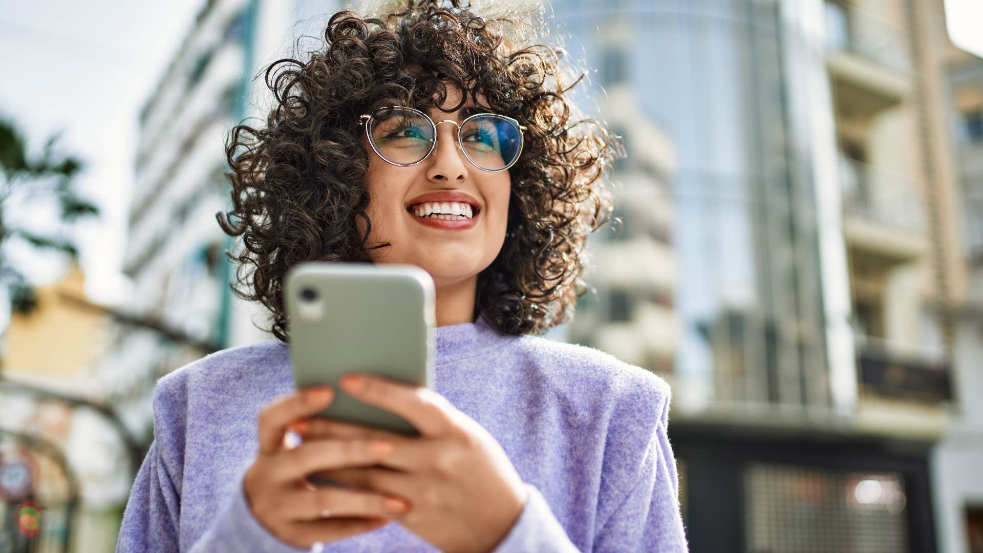 happy woman smiling and texting on her phone