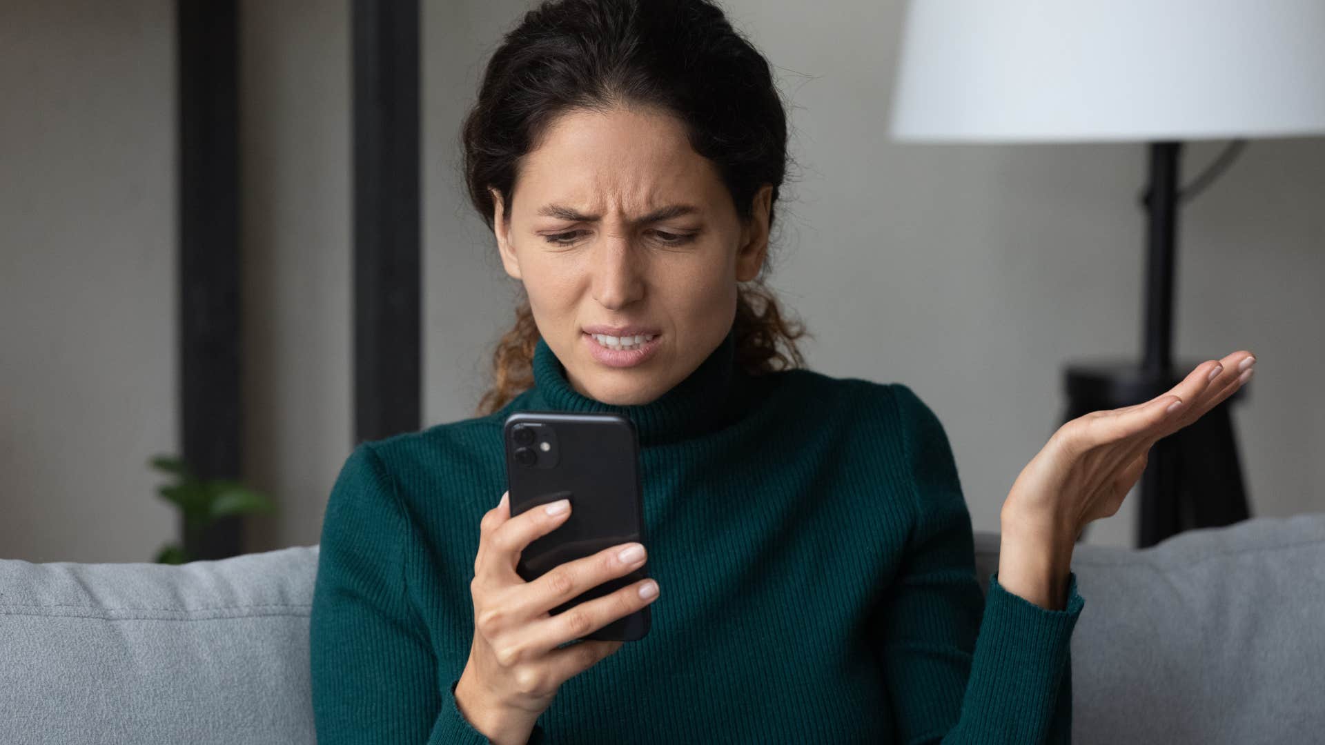 woman looking at her phone in frustration