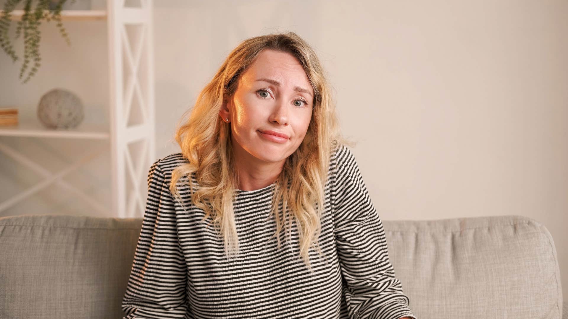 woman sitting on couch shrugging