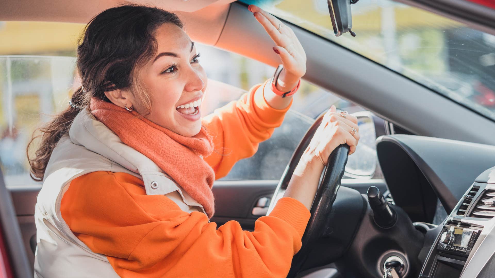 woman driving car happily waving to someone