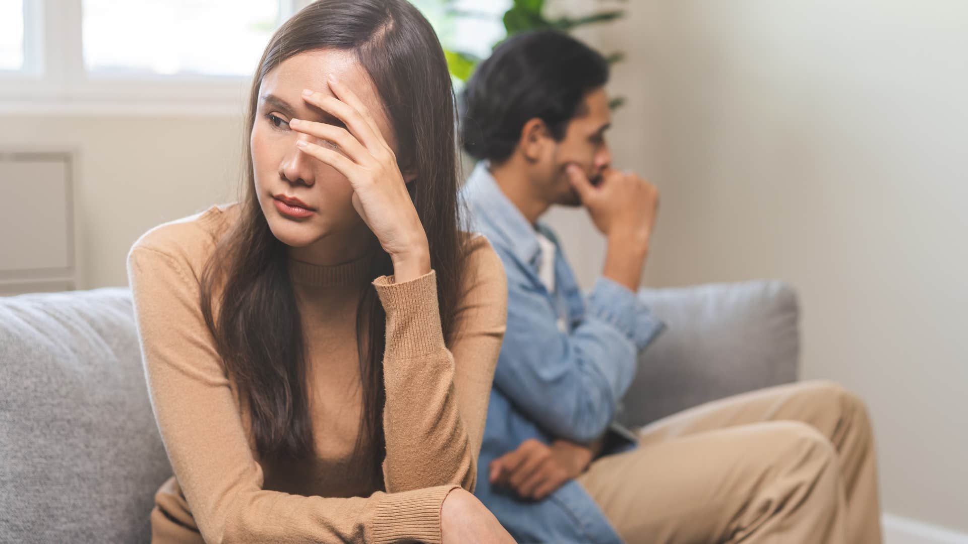 man and woman sitting on couch not speaking to each other