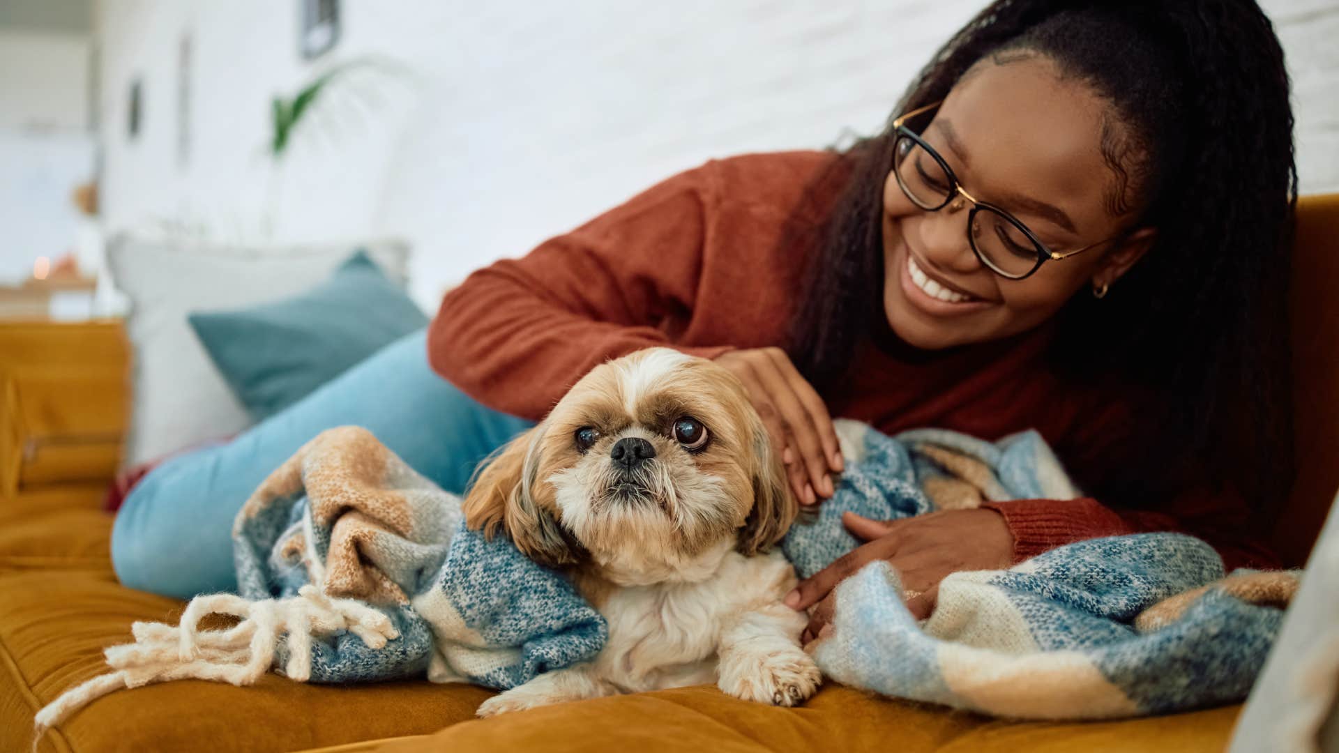 woman relaxing with shih tzu on a couch