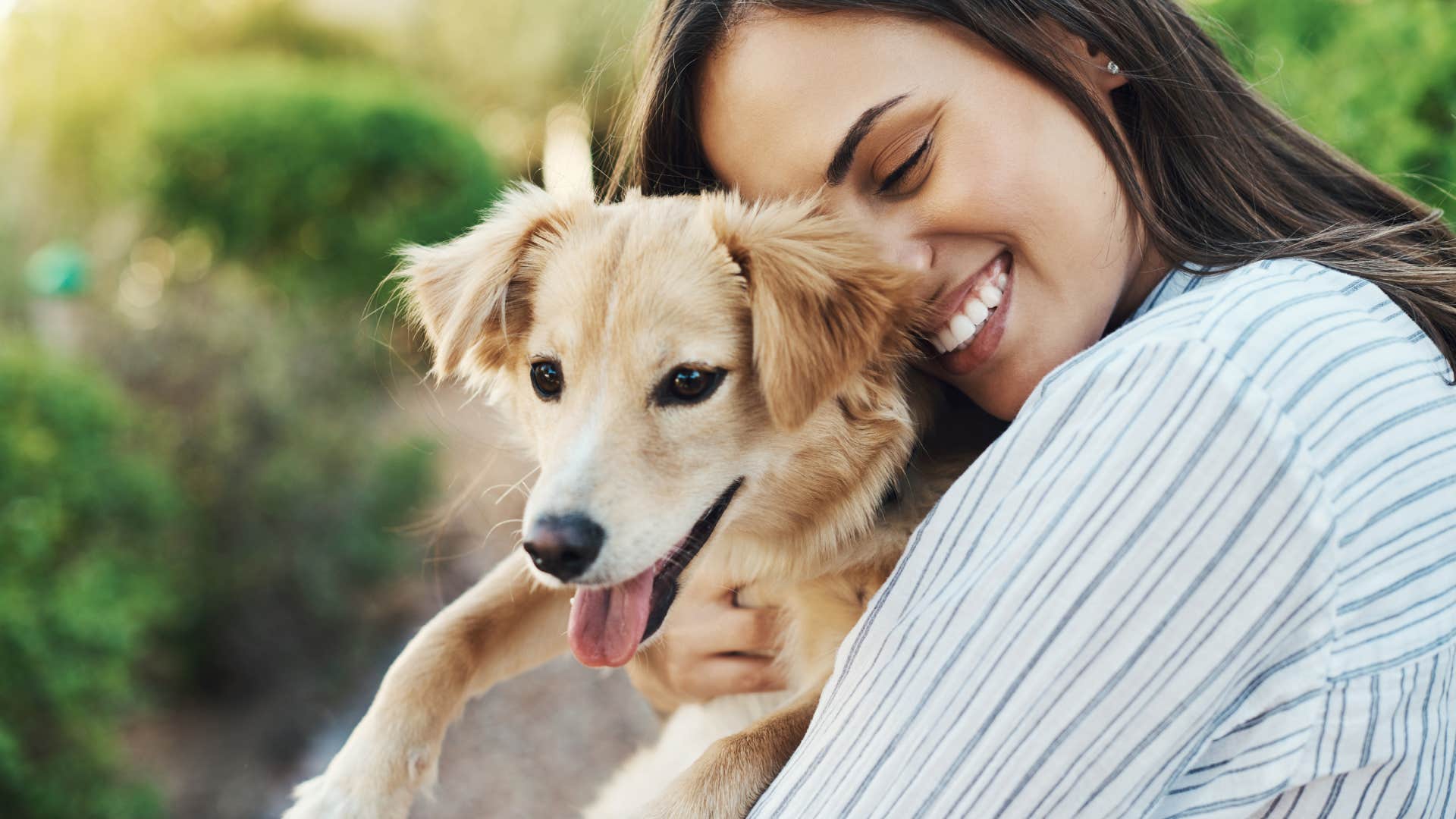 happy woman hugging dog in nature