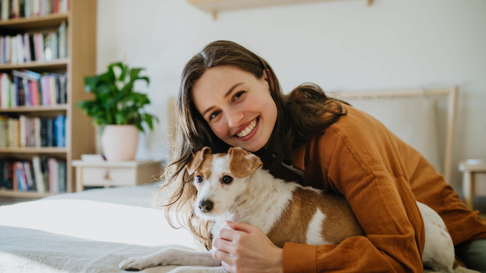 woman lying on bed petting dog