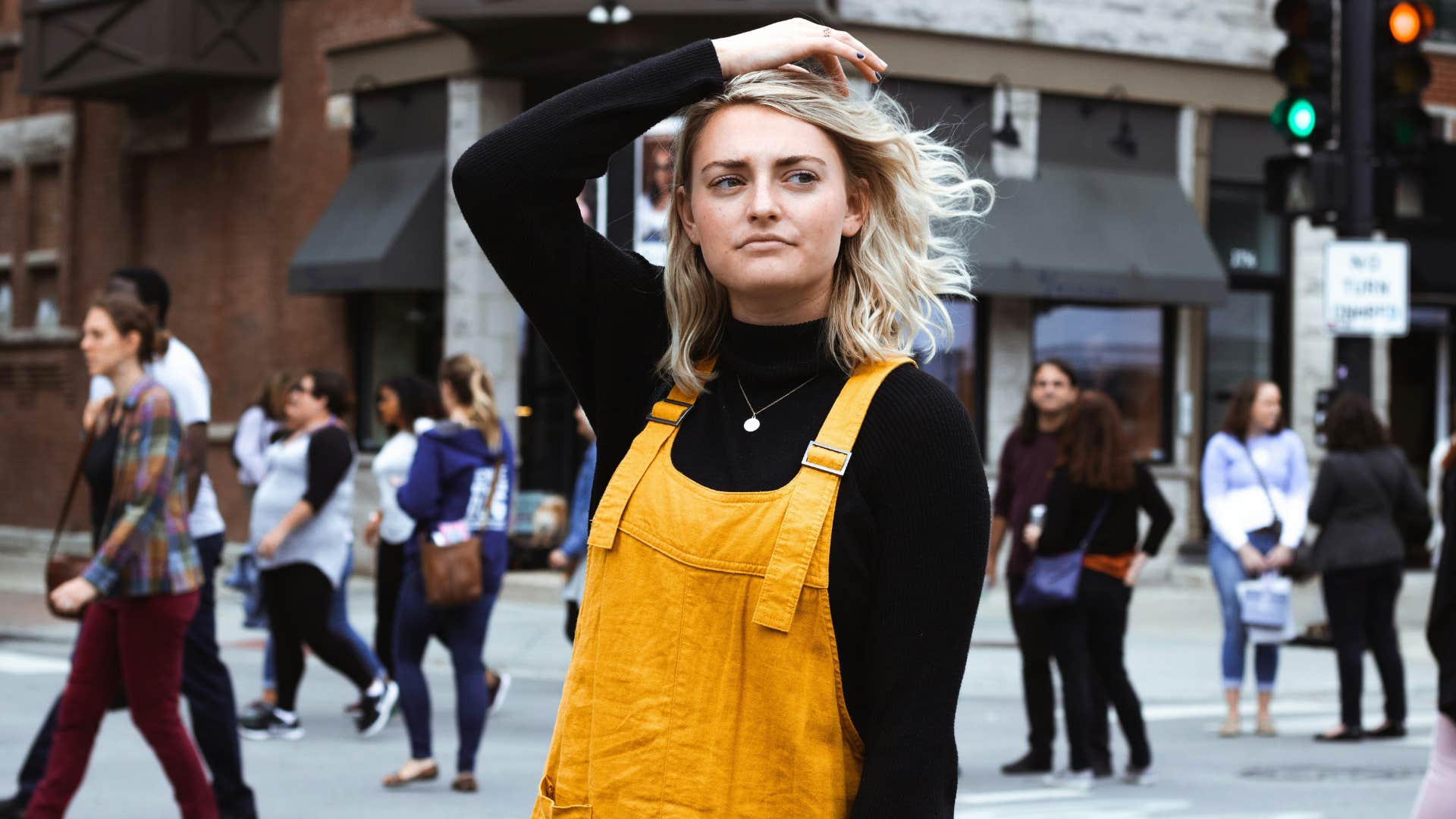 blonde woman in yellow overalls on a busy city street