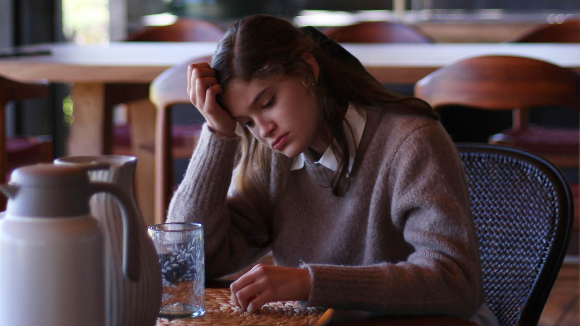 sad young woman sitting alone in a restaurant