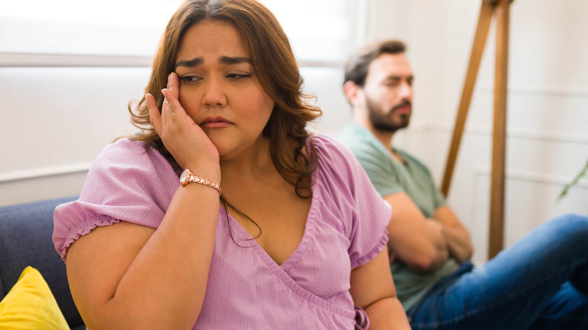 Sad woman turned away from her husband on a couch