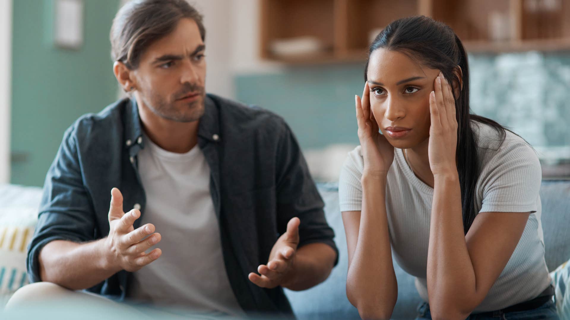 Upset woman holding her head in her hands next to her husband