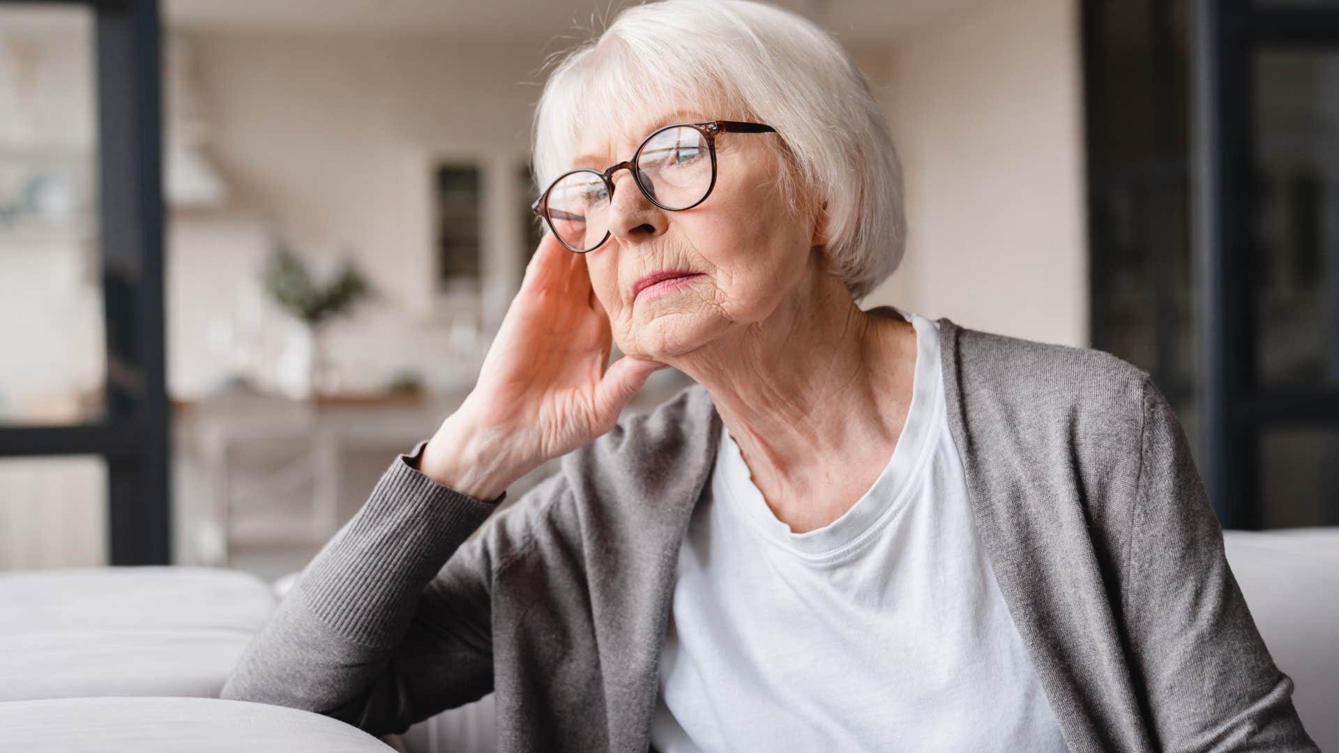 Boomer woman looking sadly out her window