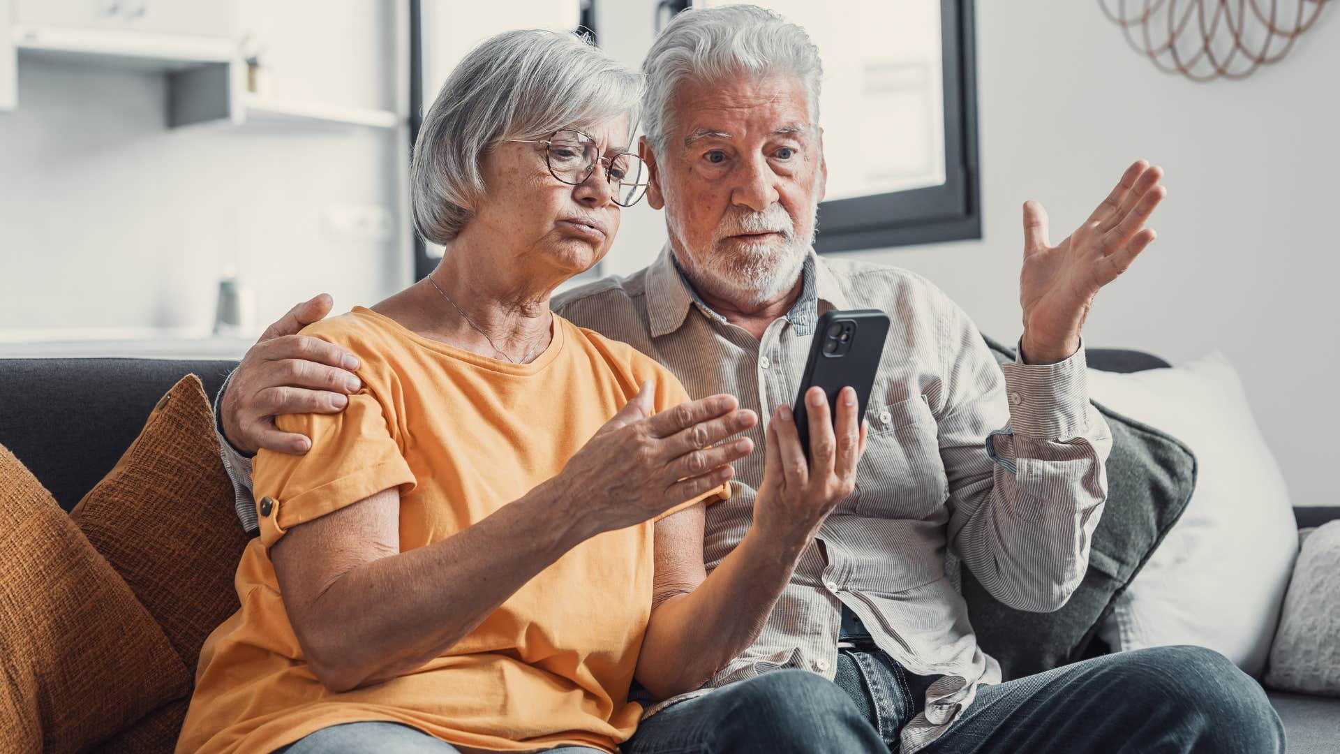 Boomer couple looking annoyed while staring at a phone