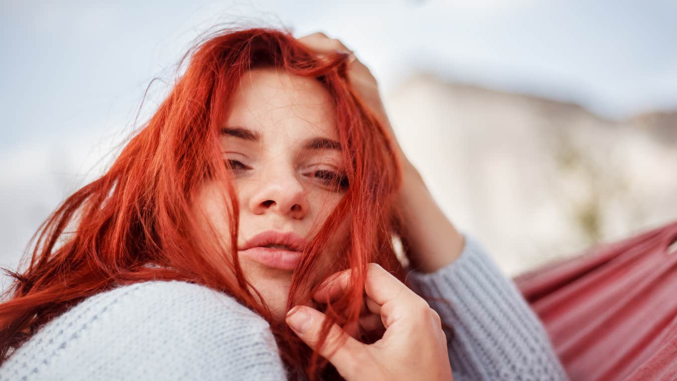 portrait of Red hair woman lying in the hammock in the apple garden against the mountain view. 