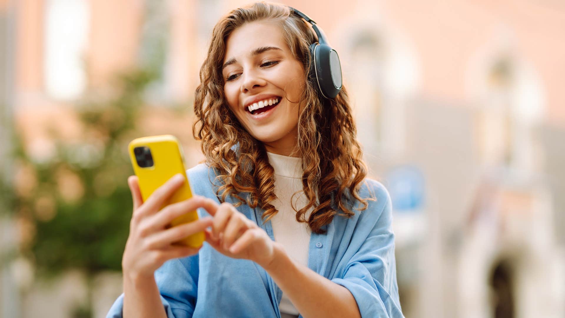 Gen Z woman smiling and texting on her iPhone