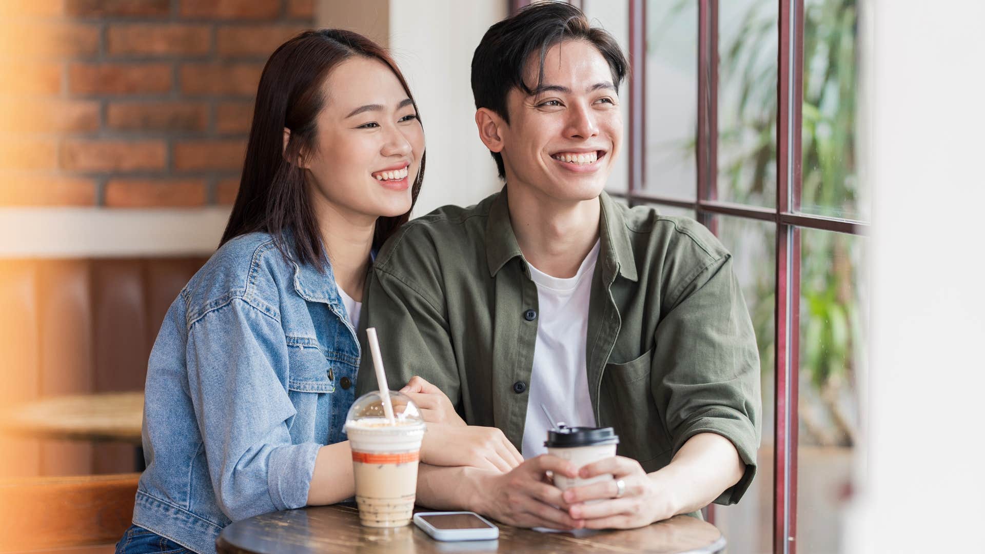 Gen Z couple smiling and sitting in a coffee shop