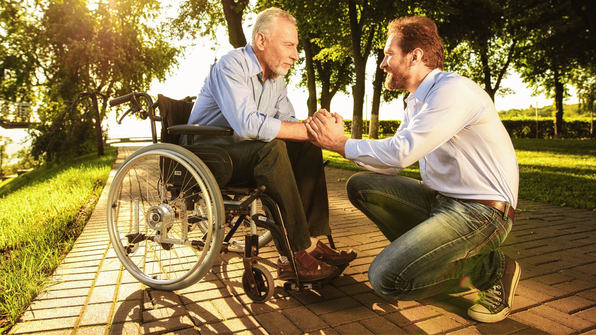 good man kneeling and talking to older man