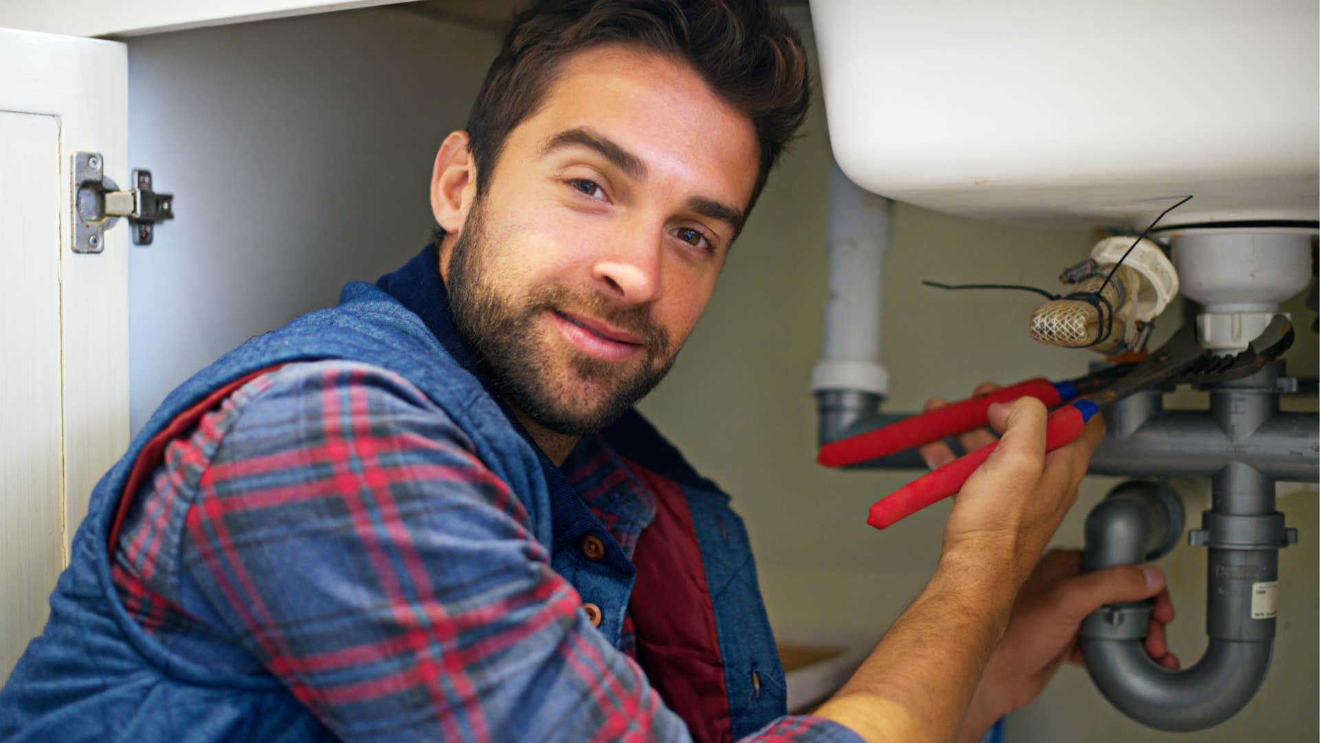 man fixing a pipe under his sink