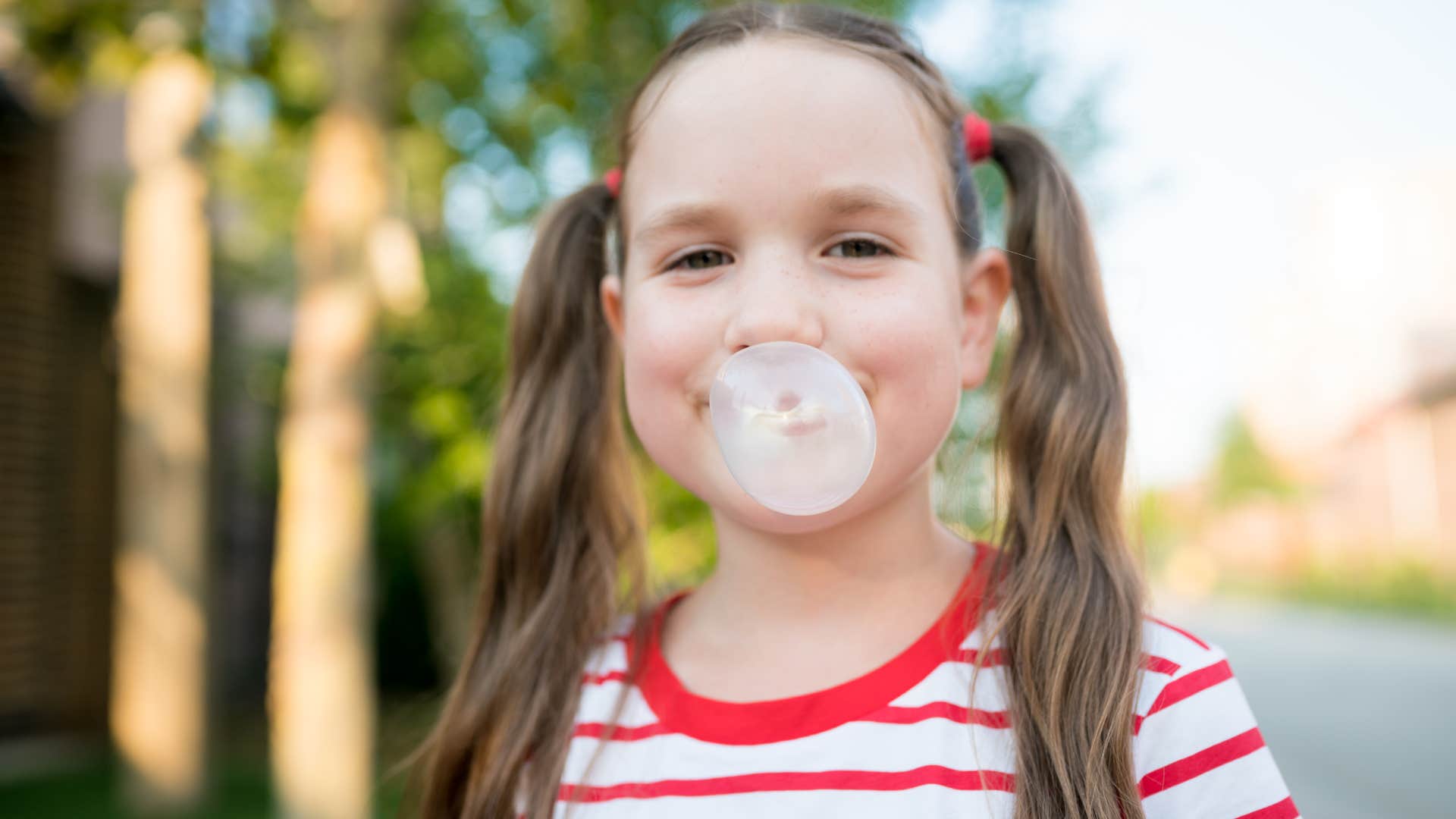 little girl smiling and blowing a bubble