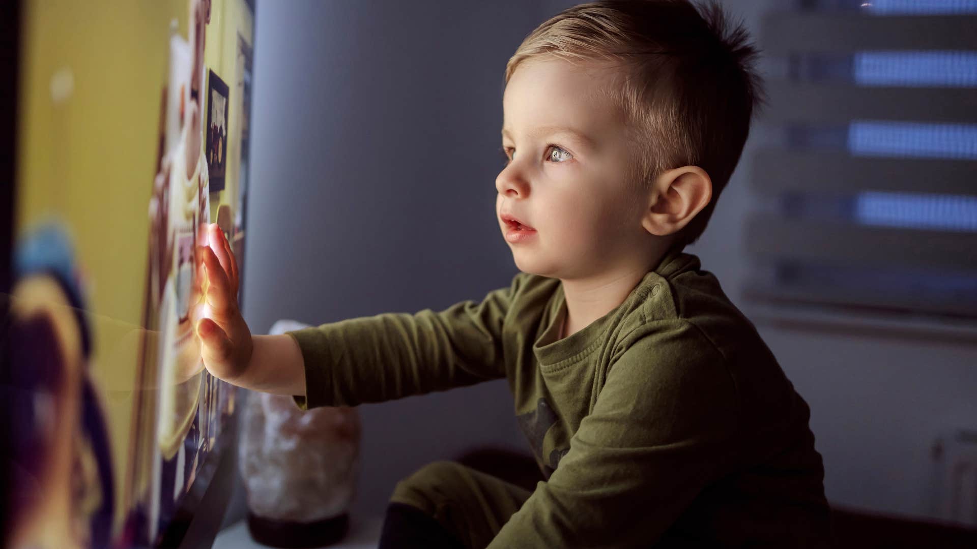 little boy sitting close to a TV