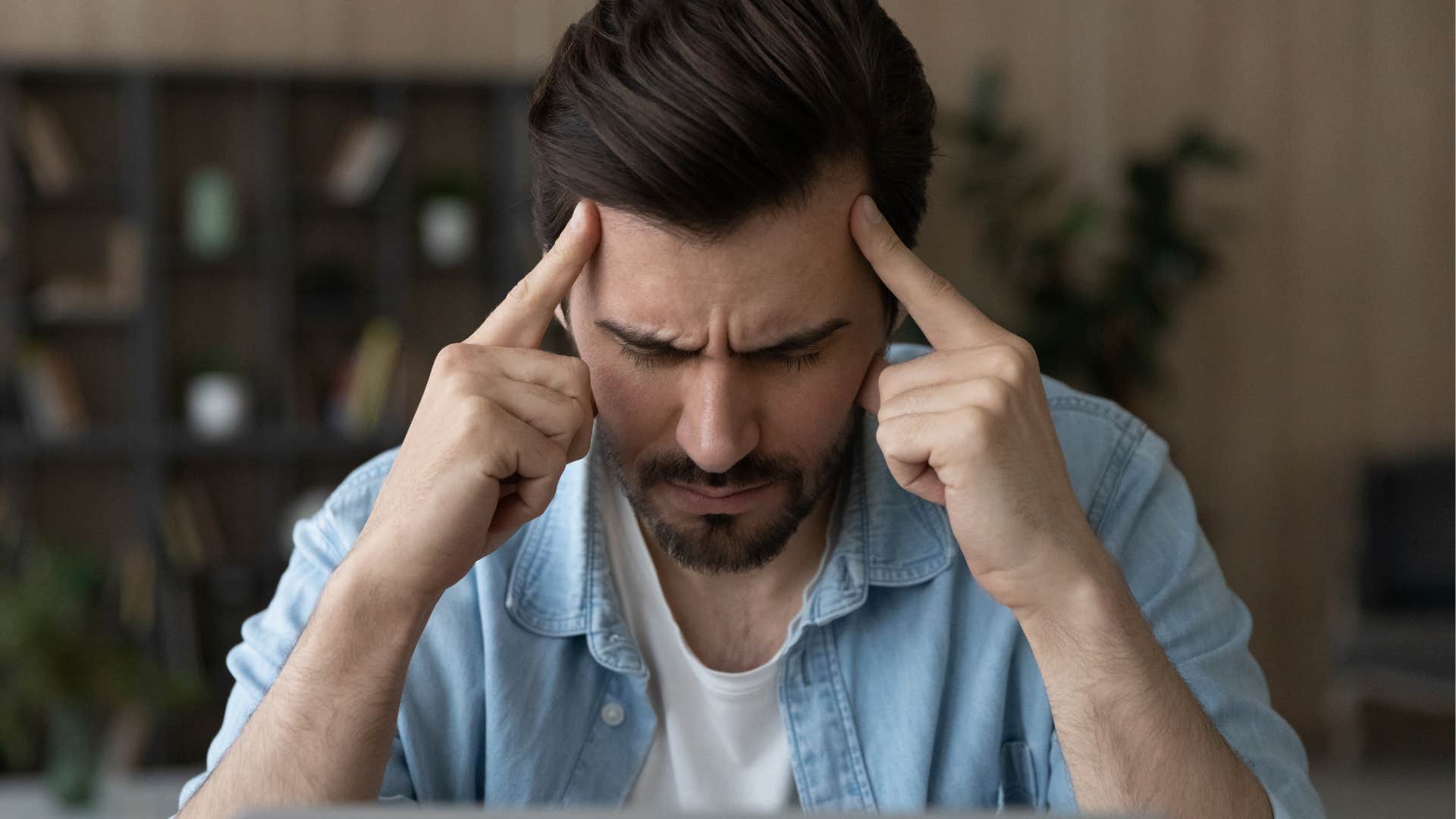 man focusing and holding his forehead