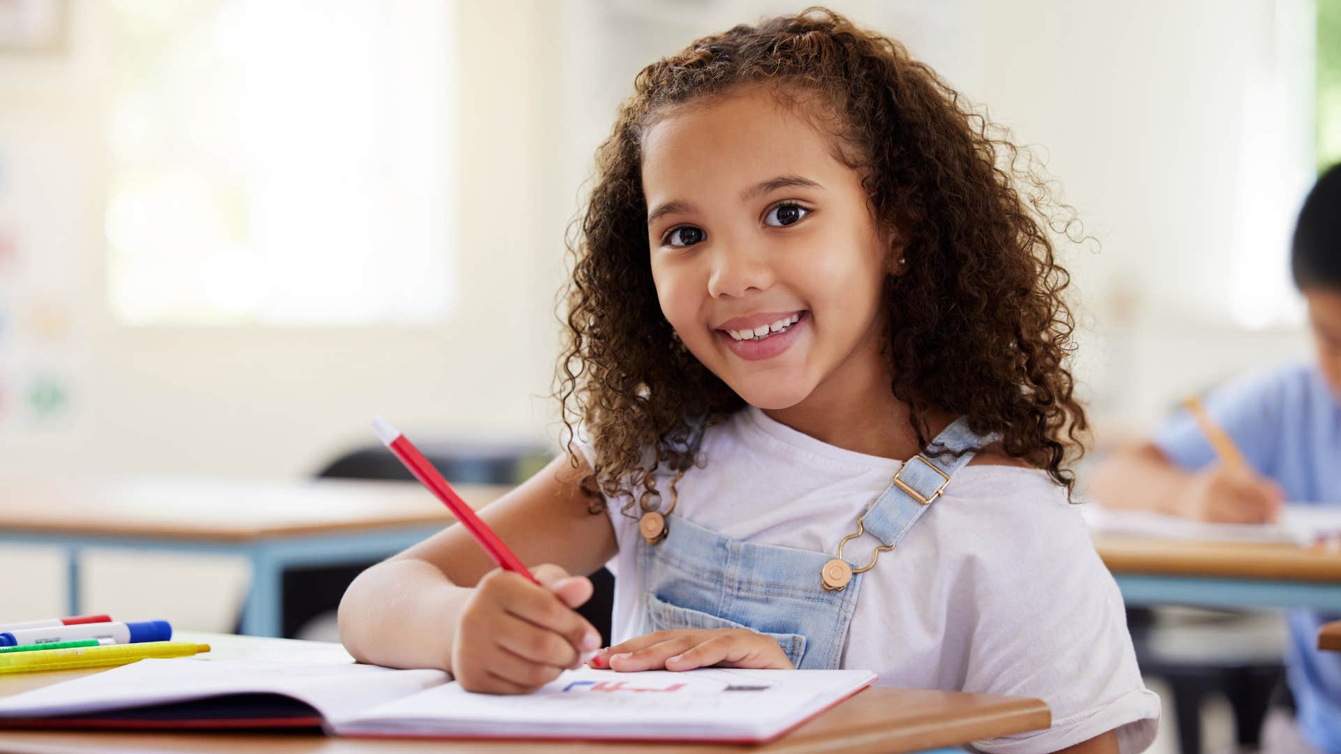 young girl smiling while writing at her desk