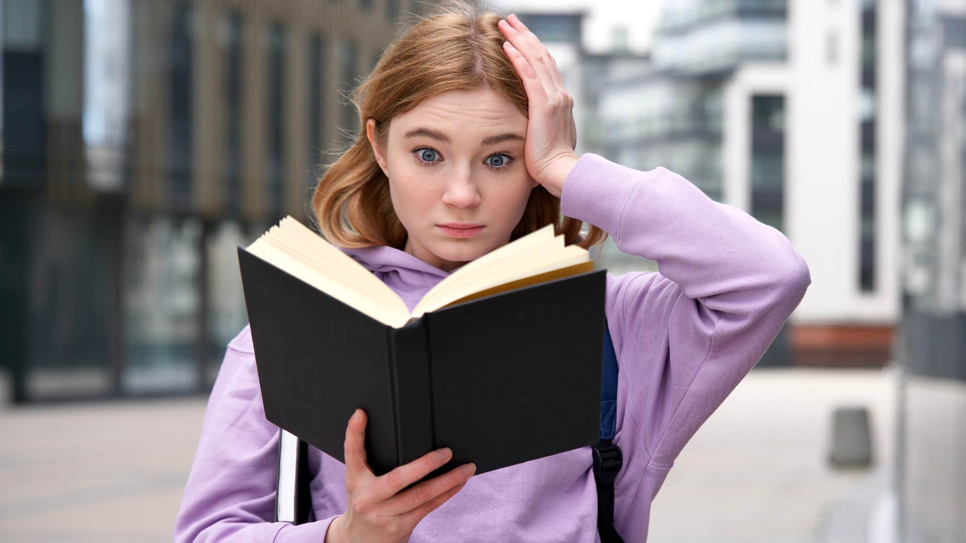 teenage girl looking shocked reading a book