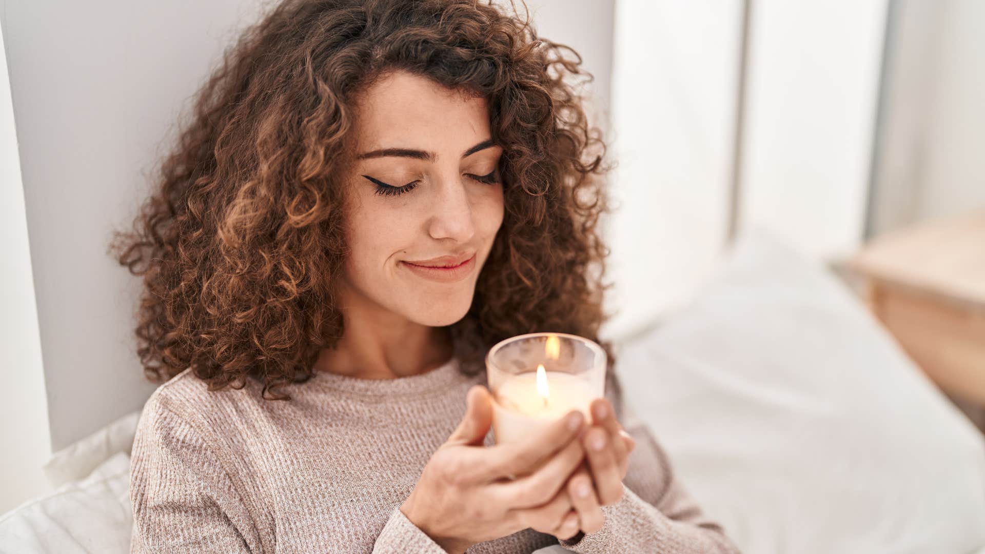 woman smiling and smelling a candle