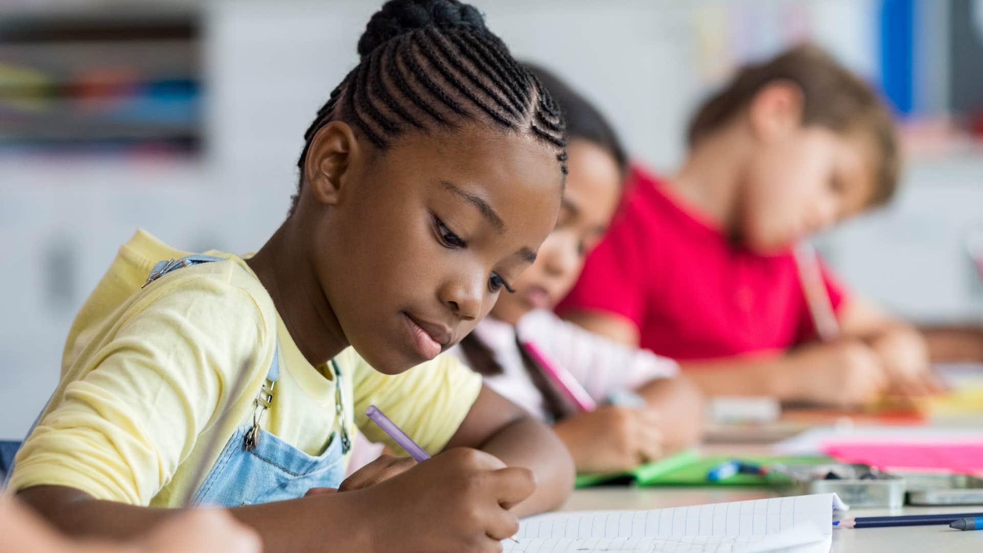 young girl focused doing homework in a classroom