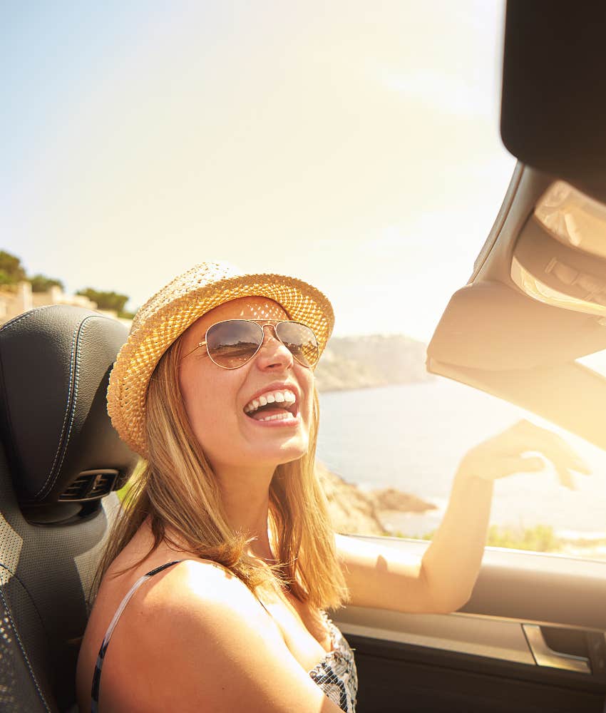 happy woman driving and smiling in a convertible car