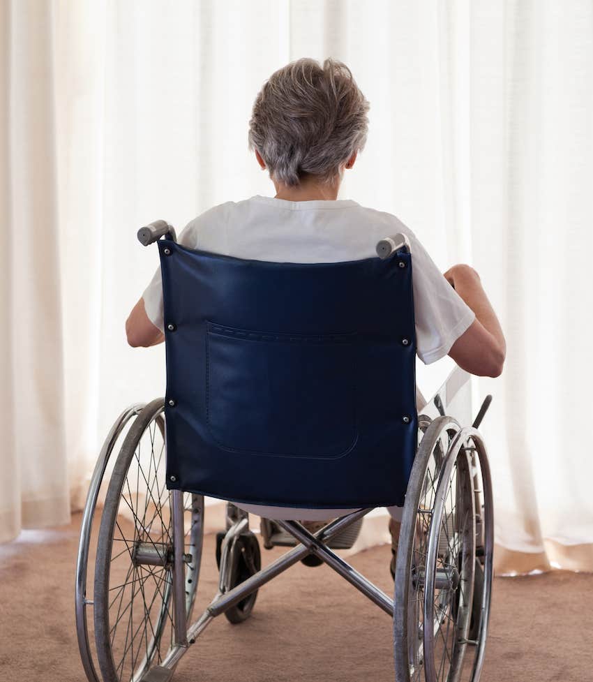 Elderly person in wheel chair sits at window to think pain from nervous system