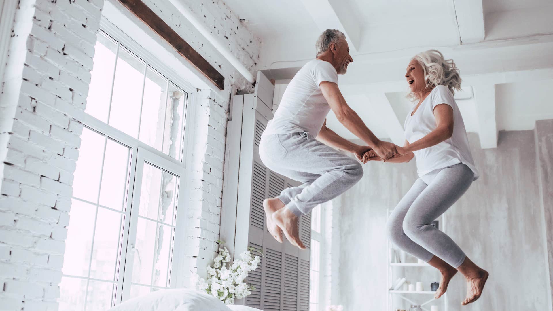 Couple laughing while jumping on bed having fun happiest marriage