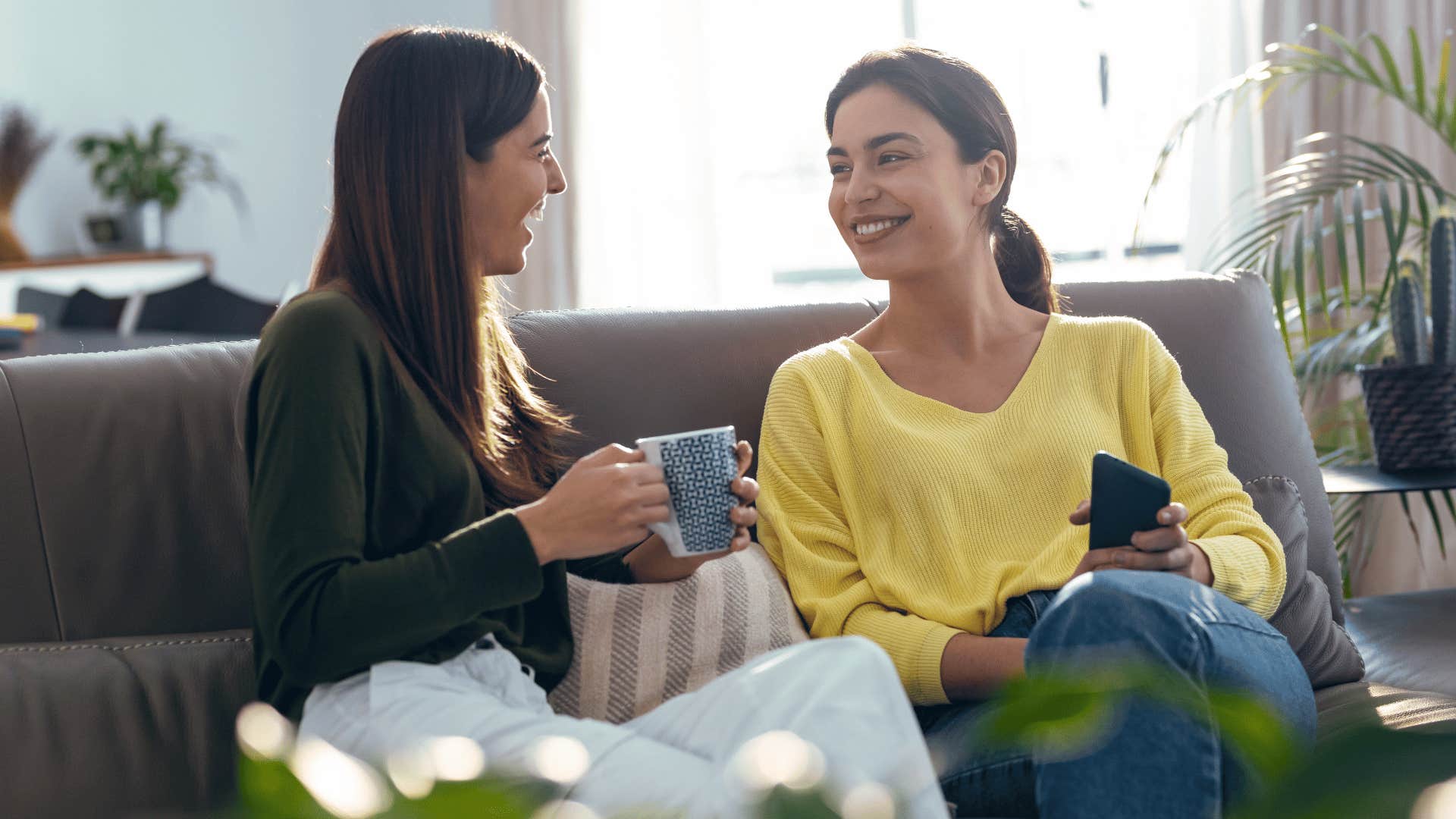 two friends chatting while drinking coffee on the couch