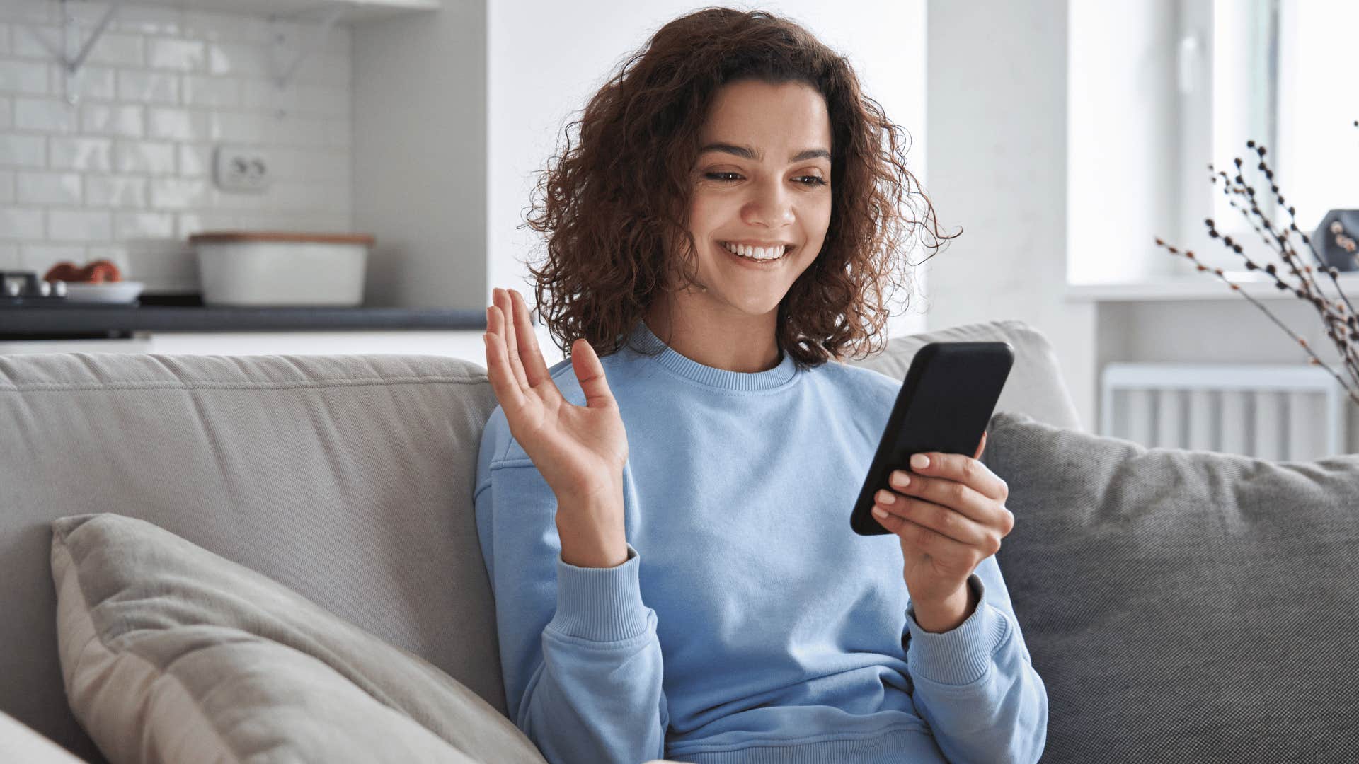 woman holding up hand while on phone