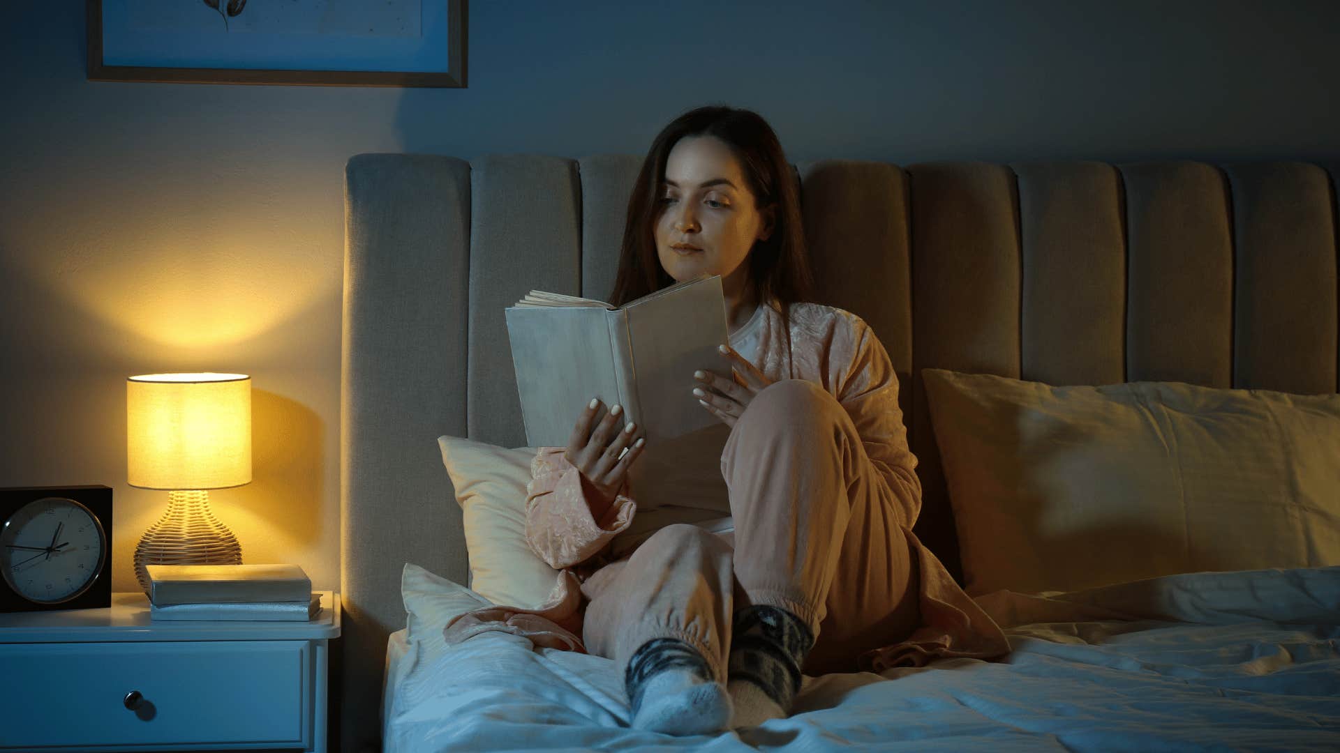 woman reading book in bed