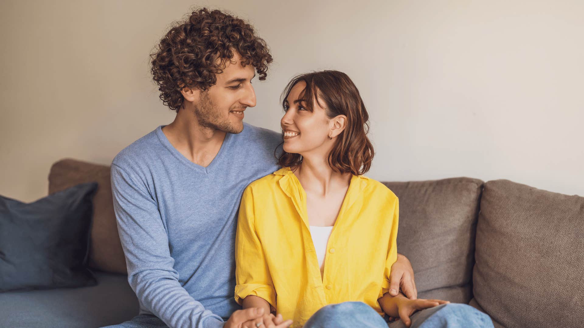 couple smiling and looking at each other on couch