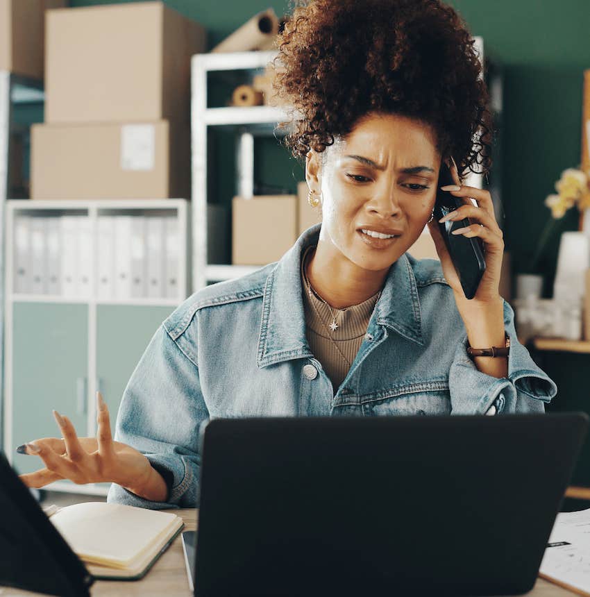 Frustrated woman on phone sitting at desk