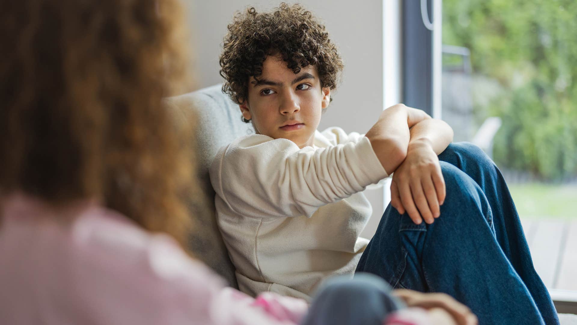 sad teenage boy sitting across from his mom