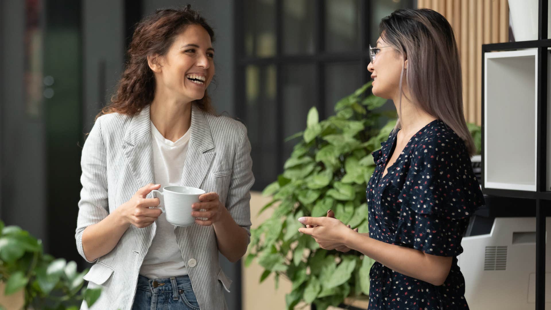 Two high value women smiling and talking at work