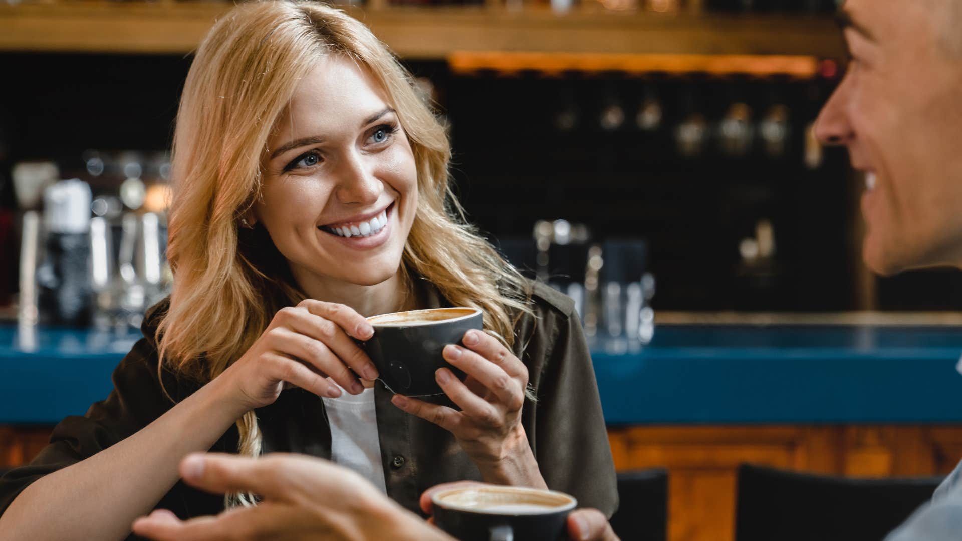 high value woman smiling and talking to a man in a coffee shop