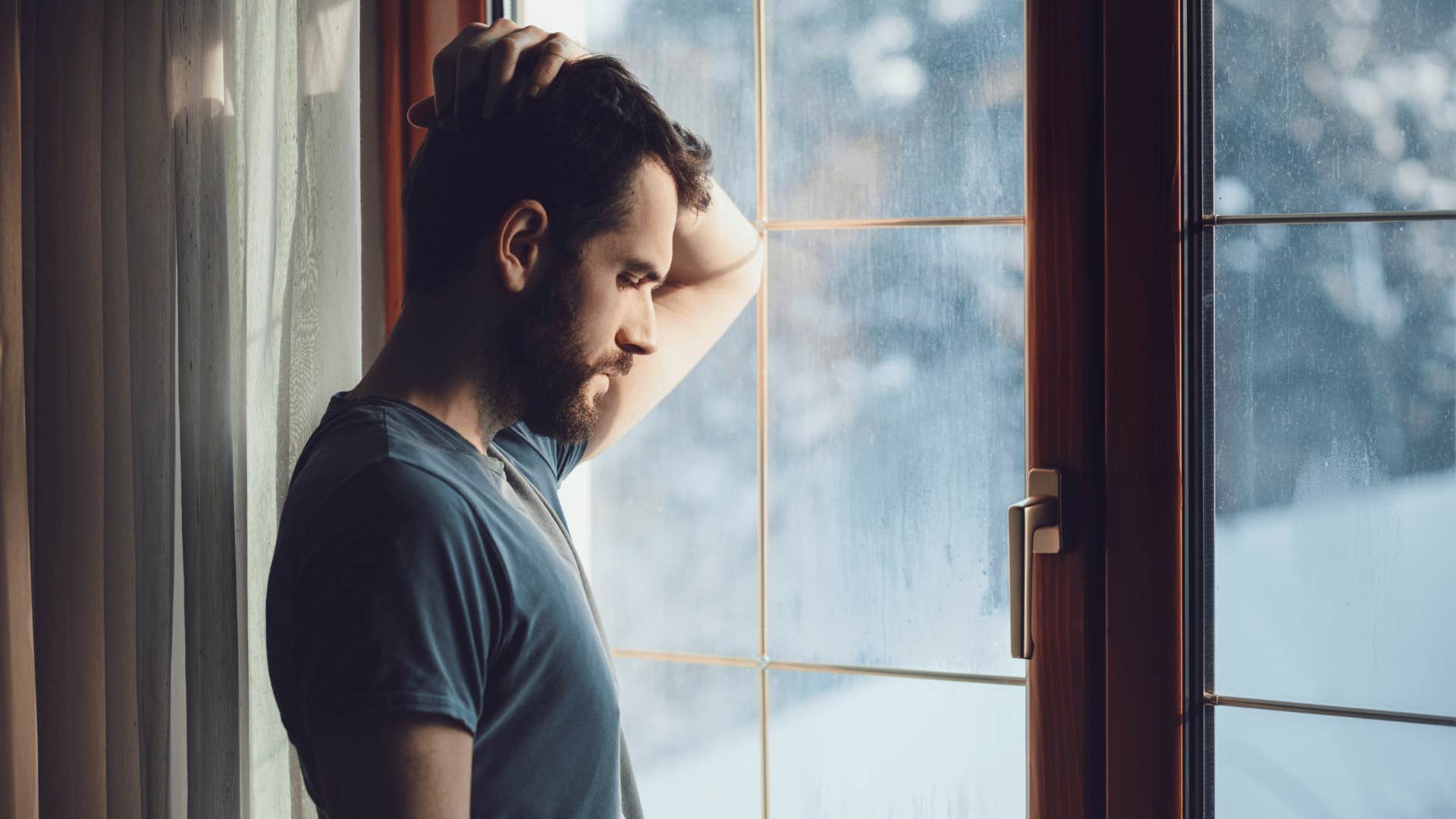 man feeling guilty looking out window