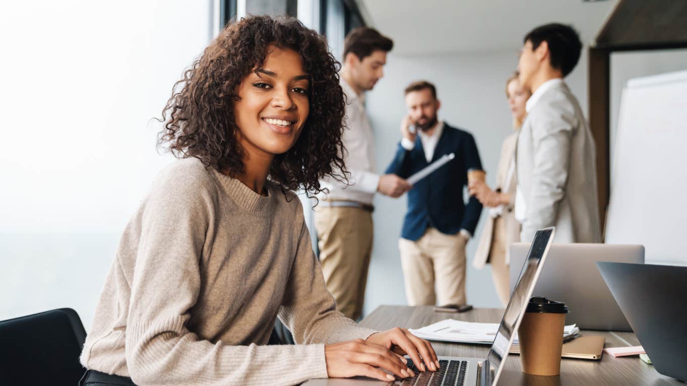 businesswoman sitting at the office table with group of colleagues in the background