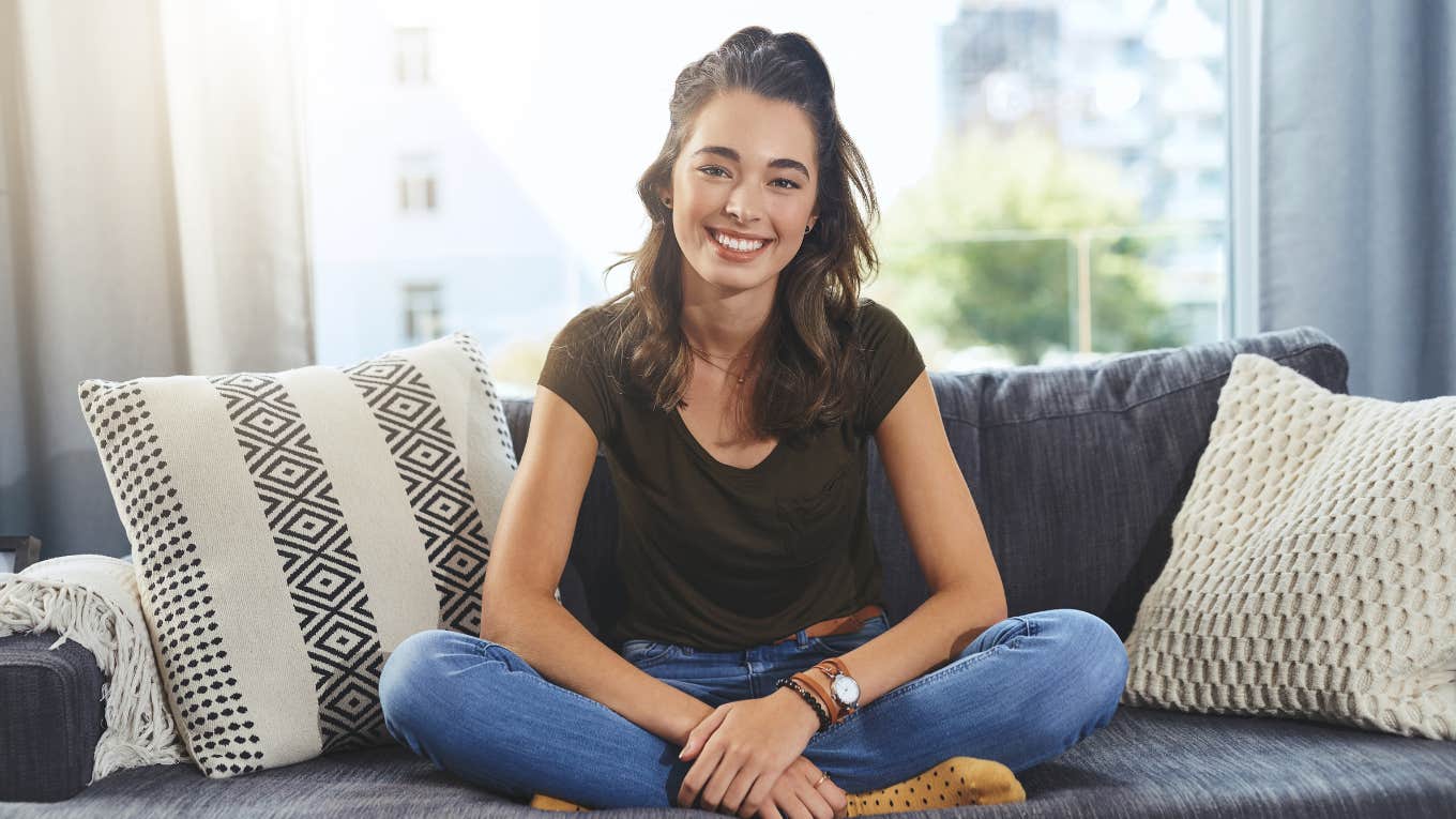 Millennial woman sitting on a couch smiling