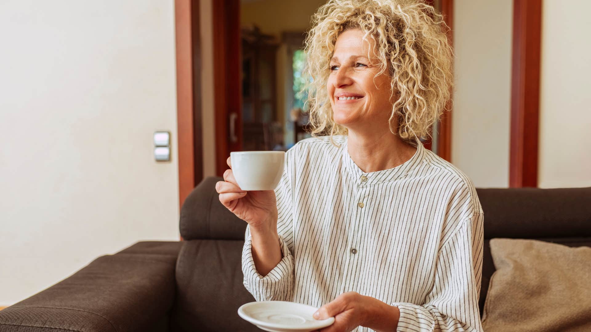 woman smiling and drinking a mug of coffee