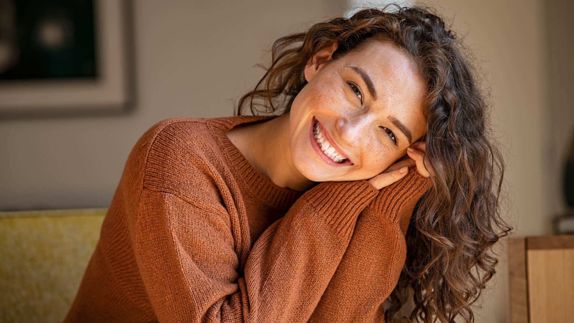 Happy young woman sitting on sofa at home